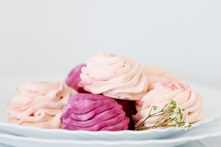 Elegant blackcurrant and apple zephyr on white plates with delicate flowers bright light