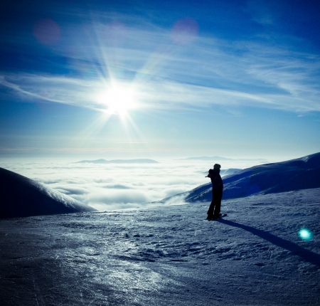 Ski traveler woman silhouette in amazing winter mountains landscape, over the clouds, opposite to sunset sky の写真素材