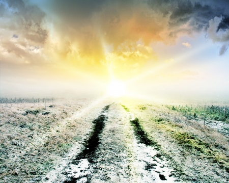 Winter snowy road leading to horizon at sunset の写真素材