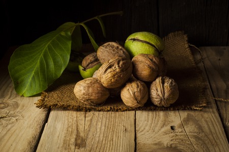Walnut kernels and whole walnuts on rustic old wooden table