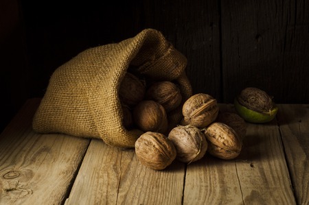 Walnut kernels and whole walnuts on rustic old wooden tableの写真素材