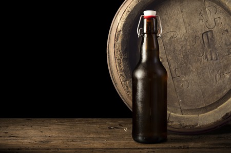Still life: old wooden pin of beer, glass of beer and wheat on the table in the cellar.