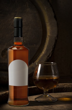 Glasses of brandy in cellar with old barrelsの写真素材