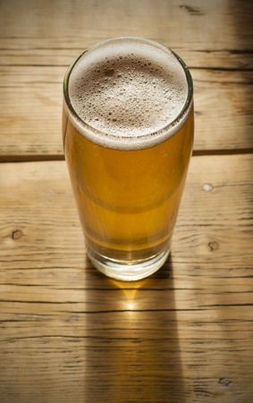 Beer barrel with beer glass on table on wooden background