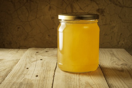honeycomb on frame with fresh honey in a vase on wooden table.の写真素材