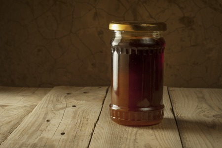 honeycomb on frame with fresh honey in a vase on wooden table.