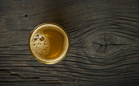 Beer, green hops and malt on a stone surface.