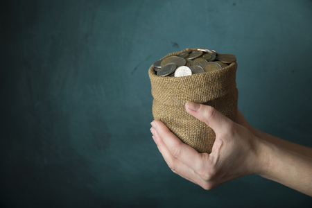 hand drops money into a glass jar for a savingsの写真素材