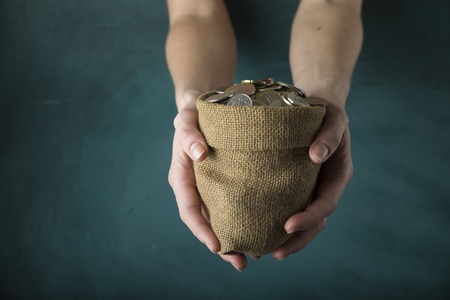 hand drops money into a glass jar for a savingsの写真素材