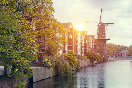 Landscape with tulips, traditional dutch windmills and houses near the canal in Zaanse Schans, Netherlands, Europeの写真素材