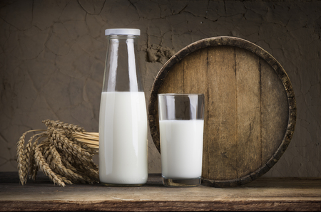 Milk glass and milk jug on the chamomile meadow pasture background in the Alps mountains, Switzerlandの写真素材