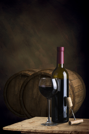 red wine bottle and wine glass on wodden barrelの写真素材