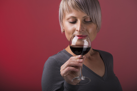 Closeup portrait of young female customer drinking red wine with eyes closedの写真素材