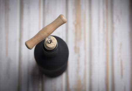 Pouring red wine into the glass against wooden backgroundの写真素材