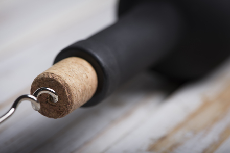 Pouring red wine into the glass against wooden backgroundの写真素材