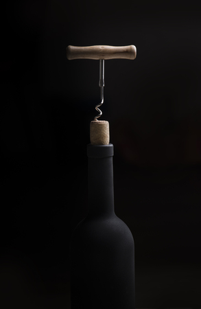 Pouring red wine into the glass against wooden backgroundの写真素材