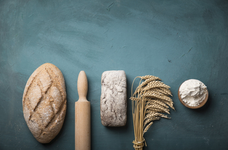 Bread border on wood with copy space background. Brown and white whole grain loaves still life composition with wheat ears scattered around. Bakery and grocery food store concept.の写真素材