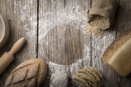 Bread border on wood with copy space background. Brown and white whole grain loaves still life composition with wheat ears scattered around. Bakery and grocery food store concept.の写真素材