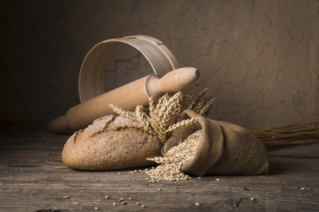 Bread border on wood with copy space background. Brown and white whole grain loaves still life composition with wheat ears scattered around. Bakery and grocery food store concept.の写真素材