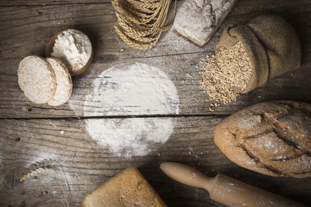 Bread border on wood with copy space background. Brown and white whole grain loaves still life composition with wheat ears scattered around. Bakery and grocery food store concept.の写真素材