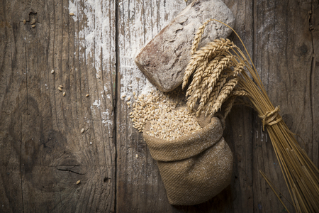 Bread border on wood with copy space background. Brown and white whole grain loaves still life composition with wheat ears scattered around. Bakery and grocery food store concept.の写真素材