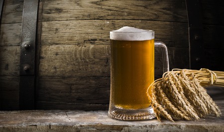 Beer in mug on wooden table near brick wallの写真素材