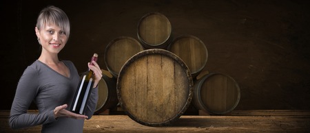 Young barefoot girl holding straw basket with a bottle of wine over natural backgroundの写真素材