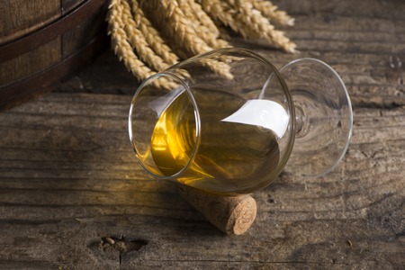 Glass of Cognac and old oak barrel defocussedの写真素材