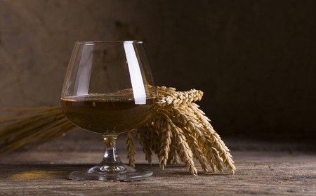 Glass of Cognac and old oak barrel defocussedの写真素材