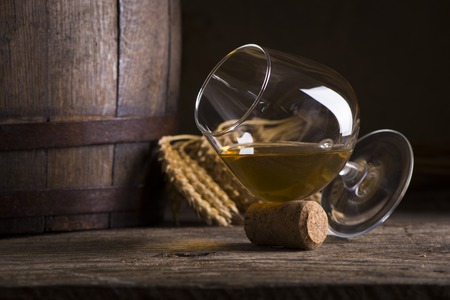 Glass of Cognac and old oak barrel defocussedの写真素材