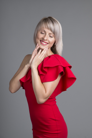 Happy girl excited. Young woman smiling very happy surprised holding head being amazed on red background. Funky young multicultural Caucasianの写真素材