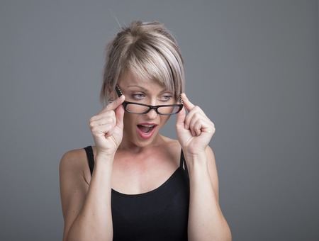 Surprised young woman in glasses over gray backgroundの写真素材