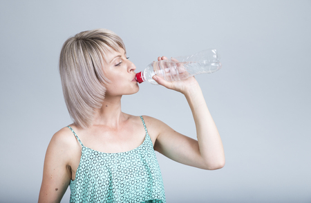Happy young woman holding an apple and a water bottleの写真素材