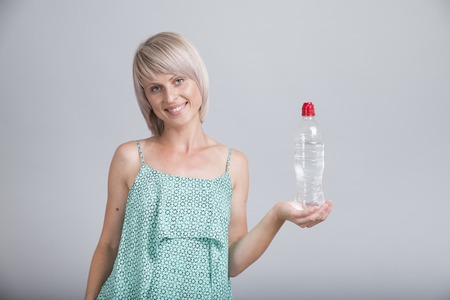 Happy young woman holding an apple and a water bottleの写真素材