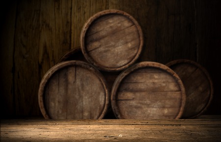 Old oak barrel on a wooden table. Behind blurred dark background.の写真素材