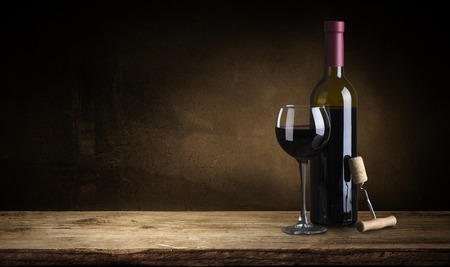 Bottle of red wine with a corkscrew. On a black wooden background.の写真素材