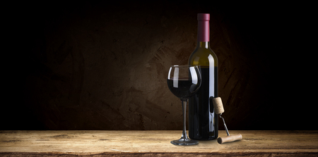 Bottle of red wine with a corkscrew. On a black wooden background.の写真素材