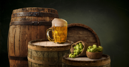 Oktoberfest beer barrel and beer glasses with wheat and hops on wooden table