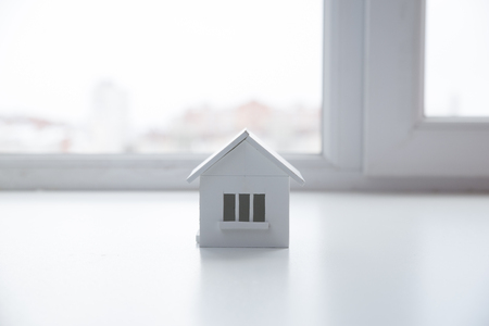 house in winter - heating system concept and cold snowy weather with model of a house wearing a knitted capの写真素材