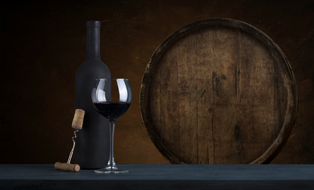 red wine bottle and wine glass on wodden barrelの写真素材