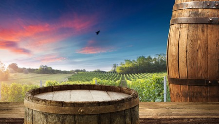Red wine with barrel on vineyard in green Tuscany, Italy