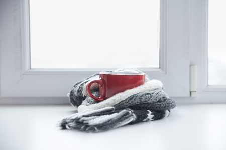 cup with a hot drink on the windowsill in the background of a winter city. Focus on the edge of the cupの写真素材
