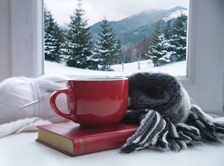 Cup of coffee or tea, smartphone and earbuds with autumn leaves near a window. Autumn playlist concept. Autumn music for rainy days