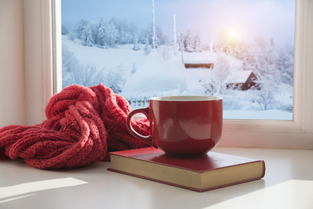cup with a hot drink on the windowsill in the background of a winter city. Focus on the edge of the cupの写真素材