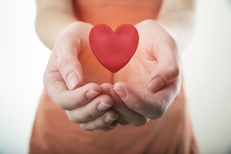 Man holding paper heart on wooden background, top view with space for text