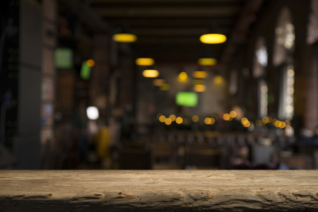 image of wooden table in front of abstract blurred background of resturant lightsの写真素材
