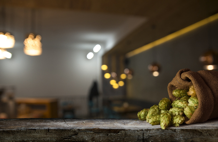 Beer brewing ingredients Hop in bag and wheat ears on wooden cracked old table. Beer brewery concept. Hop cones and wheat closeup. Sack of hops and sheaf of wheat on vintage background.の写真素材