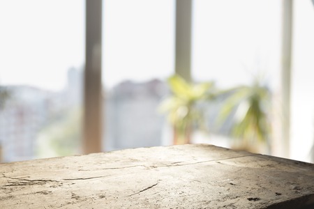 Wood table top on blur of window glass and abstract green from garden with city view in the morning background. For montage product displayの写真素材