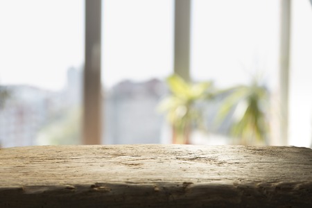 Wood table top on blur of window glass and abstract green from garden with city view in the morning background. For montage product displayの写真素材