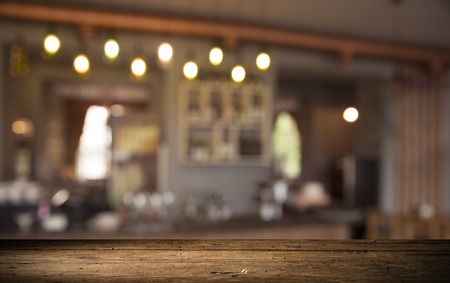 image of wooden table in front of abstract blurred background of resturant lightsの写真素材